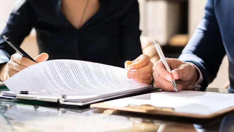 Two professionals reviewing and signing RFP documents at a desk