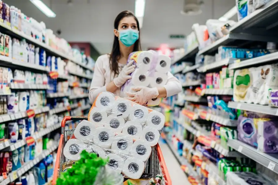 Masked shopper stockpiling bathroom tissue during a pandemic supply shortage